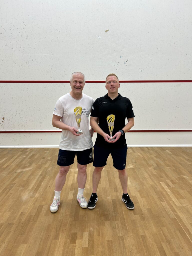 Zwei Spieler mit Pokalen im Squashcourt